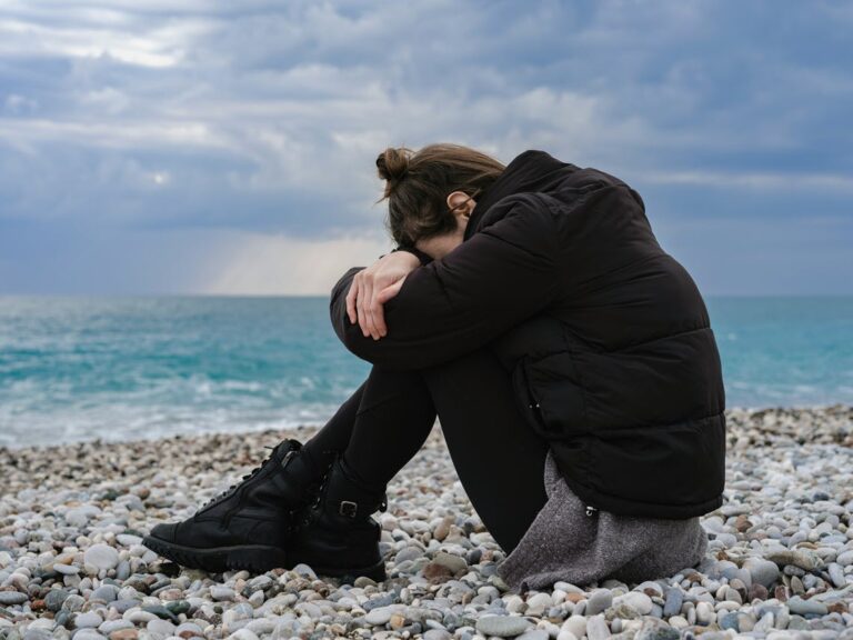 Distressed person sitting on beach