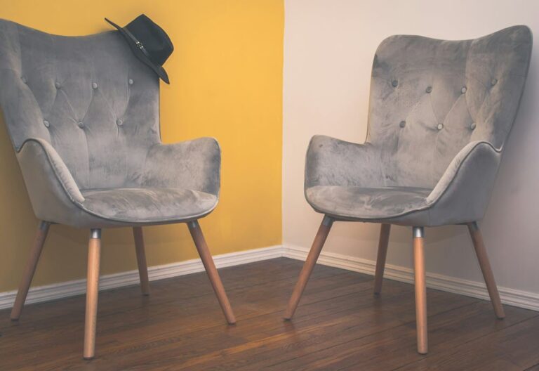 Two grey armchairs facing each other in a quiet, softly lit room