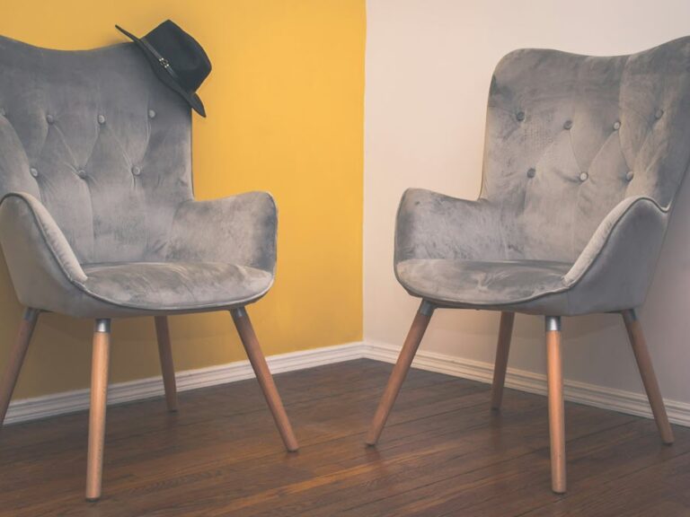 Two grey armchairs facing each other in a quiet, softly lit room