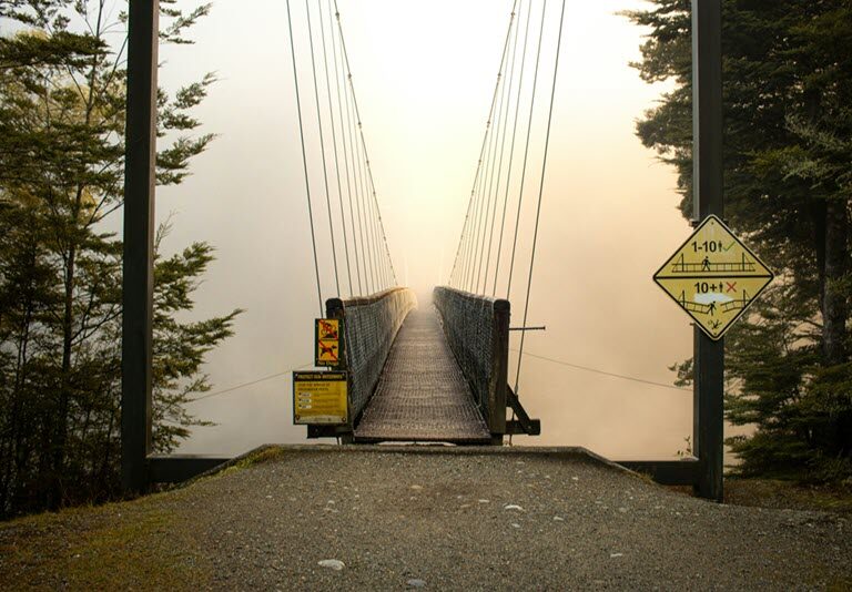 A wooden footbridge stretching into golden mist, its far side hidden from view