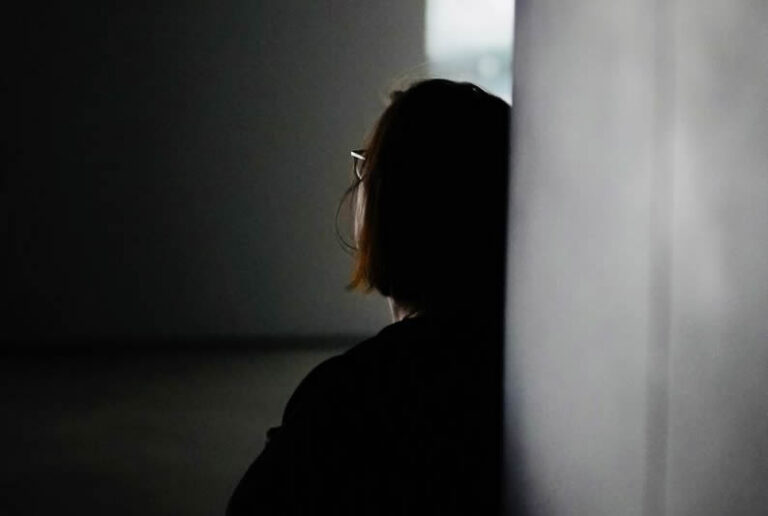 a woman leaning against a wall looking away