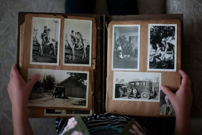 Hands opening an old family photo album of black and white photographs